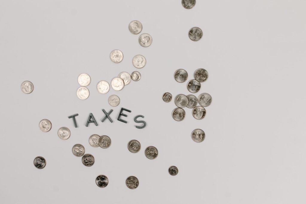 Scattered coins surrounding the word Taxes, representing NRI mutual fund tax rulesCaption: Understand the tax rules on Indian mutual fund investments, including capital gains