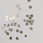 Scattered coins surrounding the word Taxes, representing NRI mutual fund tax rules